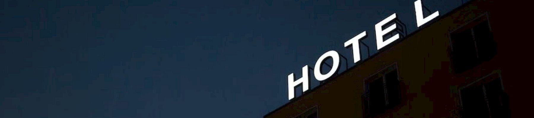 A building with a neon sign that reads "HOTEL" is visible against a dark sky, with minimal window details shown.